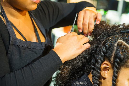 Close up african hairstylist braided hair of afro american female client in the barber salon. Black healthy hair culture and Style. Stylish therapy professional care concept. Selective focus.