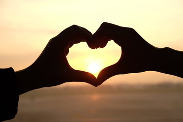 Fototapeta premium Heart shape from two hand with sunrise background.