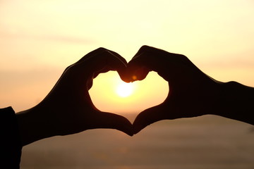 Obraz premium Heart shape from two hand with sunrise background.