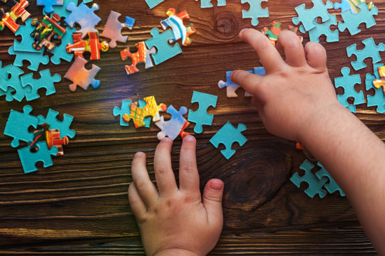 child's hands, puzzles on wooden background. preschool education, puzzle game.