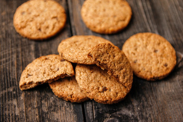 Integral cookies with cereal, dried fruit and chocolate on old wooden table