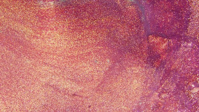 Colorful sparkling paints mix in beautiful patterns. Oil ink of gold, red, purple and other colors spread on the surface and mix one into another creating amazing textures and design.