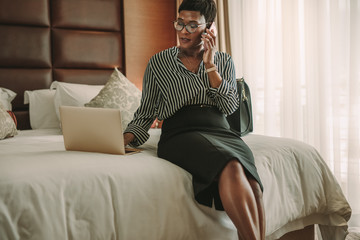 Obraz premium Business woman in hotel room using laptop and smartphone