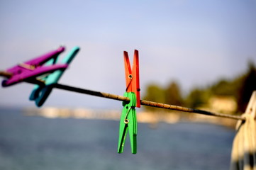 closeup of colourful clothespins hung on a laundry line rope on a blue seaside background