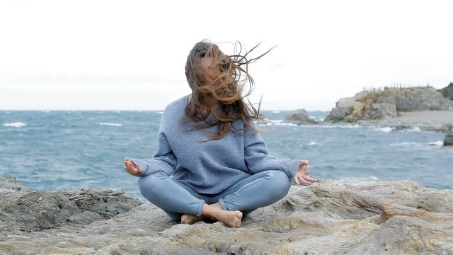 Angry woman trying to practice yoga in a windy day on the beach