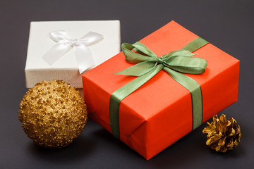 Gift boxes, christmas ball and cone on black background