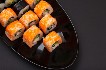 Uramaki California. Sushi rolls on a plate with black background.