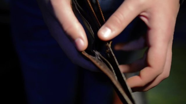 Young man opens  the empty wallet , conceptual footage of underpaid work, shallow depth of field.