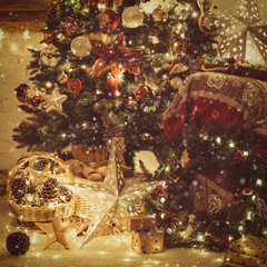 Christmas tree with baubles, stars, pine cones, lights. Decorated living room, fireplace with wood mantelpiece, cosy armchair with read throw, wooden ornaments, wreath, toned, selective focus