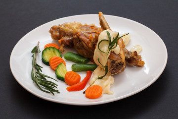 Rabbit legs baked in white wine with bechamel sauce on a ceramic plate.