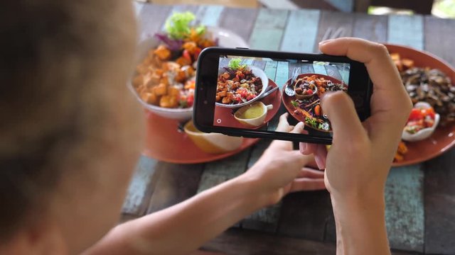 Female Food Blogger Taking Photo Of Healthy Food Using Smartphone In Restaurant