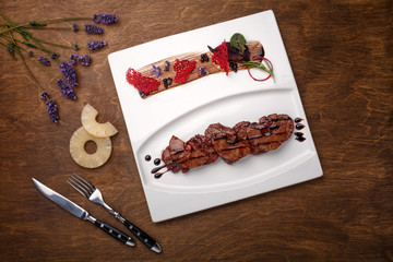 Roasted meat with pineapple in balsamic sauce on a brown wooden board