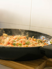 Mixing quinua with onion, red and green pepper and courgette in a frying pan. Cooking quinua with vegetables, recipe of quinua and vegetables