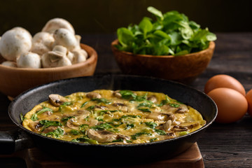 Omelette with mushrooms and cheese, on dark wooden background.