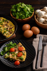 Omelette with mushrooms and cheese, on dark wooden background.