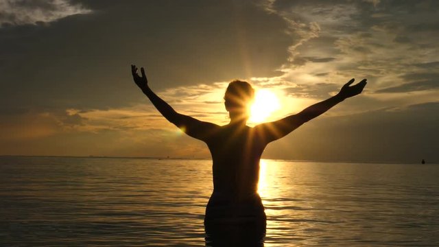 Motivational Uplifting Concept. Woman With Arms Raised At Sunset On The Beach In The Sea.