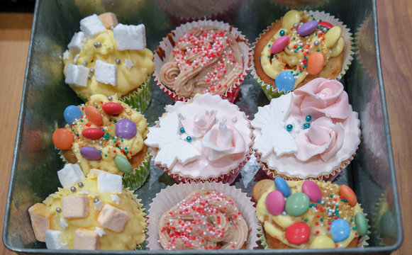 9 cupcakes diff&eacute;rents avec d&eacute;coration icing bonbon et cr&egrave;me dans une boite en fer vintage