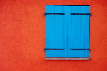 Obraz na płótnie Canvas Blue wooden closed shutters on window on orange wall, copy space