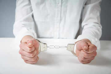 Arrested man handcuffed hands at the back isolated on gray background.
