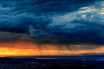 Fototapeta na wymiar Rain at Sunset over Lake Constance and City