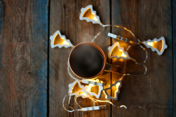 A cup of hot coffee. Top view. Flat lay. Rustic table with garland around. Cozy home background.