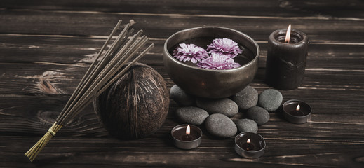 Singing bowl with candles with pebbles on dark wooden background