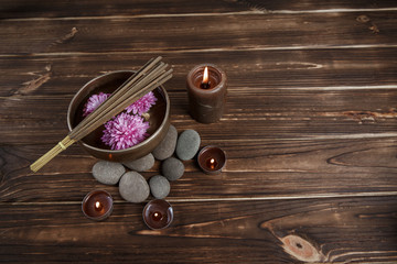 Fototapeta na wymiar Singing bowl with candles with pebbles on dark wooden background