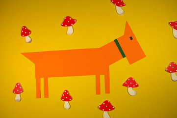 Cut paper on yellow background.Little dachshund puppy and red mushrooms.