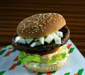 Bocadillo con un panecillo de semillas, una hamburguesa,lechuga, salsa mayonesa, tomate y cebolla.