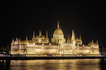 Fototapeta na wymiar Scenic view of Hungarian parliament in ancient historic tourist city Budapest and famous river Danube in nightlight illumination in Hungary