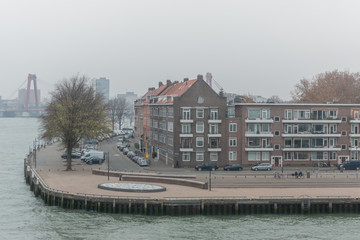 Neighbourhood quay in the city centre of Rotterdam on a hazy overcast day with in the background a bridge and city constructions