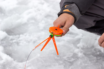 A man holds a small orange fishing pole for fishing.