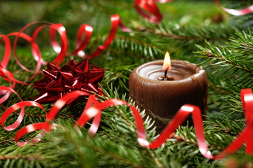 Wooden background with branches of a Christmas tree and a red candle.