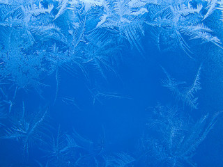 Beautiful crispy frost structure on a window with cold blue gradient light
