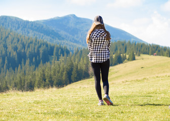 Back view young woman with backpack on top of mountains looking to nature