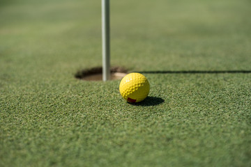 Golf field with yellow ball near the hole