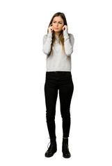 Full-length shot of young girl covering ears with hands. Frustrated expression on isolated white...