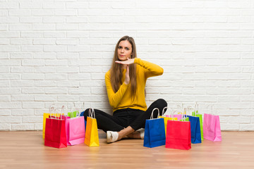 Young girl with lot of shopping bags making stop gesture with her hand to stop an act