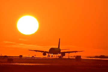 Fototapeta na wymiar Good luck　夕日を背景に着陸する航空機　　Aircraft landing on the sunset background　　The most beautiful Radiates the glow of the sunset Flying happiness Aircraft image carrying good luck