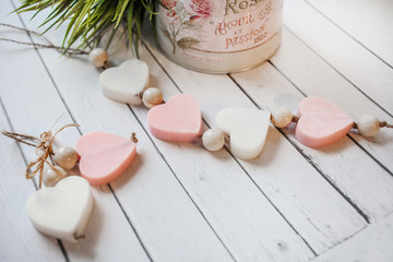 Flat lay composition with handmade soap bars in the shape of hearts on white wooden background