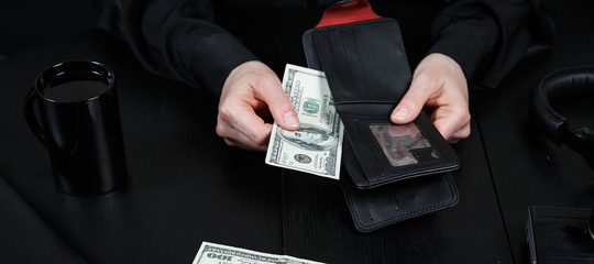 Hand in suit takes out dollar money from a wallet