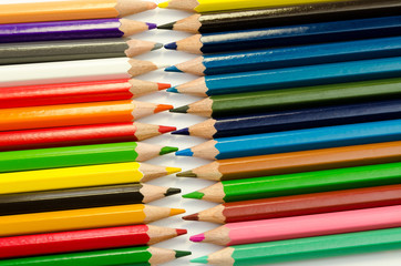 Color pencils pink light blue green yellow and red on white background.