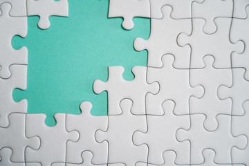 Fragment of a folded white jigsaw puzzle and a pile of uncombed puzzle elements against the...