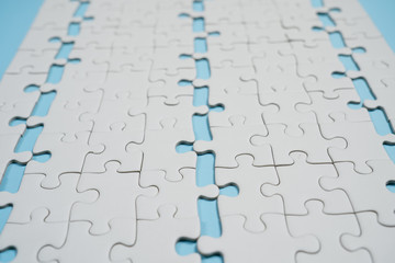 Fragment of a folded white jigsaw puzzle and a pile of uncombed puzzle elements against the...