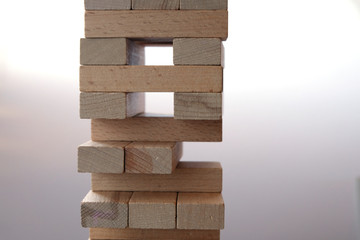 Tower of wooden cubes on a light background. Concept - successful construction. Copy space. Financial Pyramide. Crisis conditions. Board game - Genga.