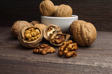 Handful of Walnuts in white bowl on wooden background