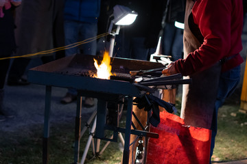 A craftsman working with fire and a hammer on a glowing iron. middle age, flame, metal, handmade;
