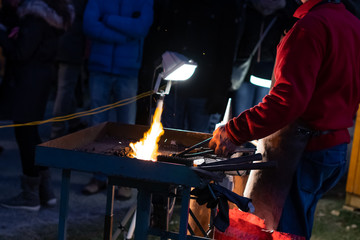 A craftsman working with fire and a hammer on a glowing iron. middle age, flame, metal, handmade;