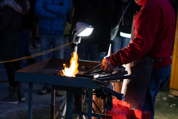 A craftsman working with fire and a hammer on a glowing iron. middle age, flame, metal, handmade;
