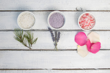 Aromas of bath salt. Rose, lavender and pine near bowls with colorful bath salt on light wooden background top view copy space